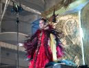 Girl dressed in a red costume standing on top of a Carnival float in Aguilas