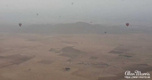 Air balloons can be seen through low clouds as they rise above the desert. Air balloons can be seen through low clouds as they rise above the desert.