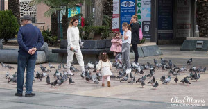 A little girl chasing pigeons in a square in Ceuta.