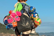 Man selling beach balls, buckets & hats on Copacabana Beach.