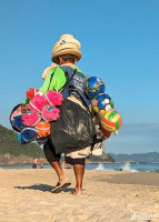 Man selling beach balls, buckets & hats on Copacabana Beach.
