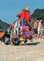 Man selling towels, blankets & bags on Copacabana Beach.