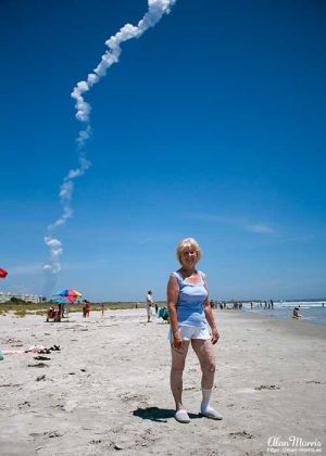 A rocket plume rises into the sky at Cape Canaveral behind Jean Morris.