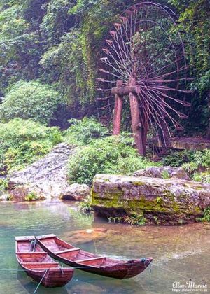 A waterwheel & two boats on the Xiangxi River in the Xiling Gorge.