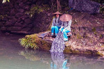 Two girls from the Tribe of the Three Gorges wash clothes in the Xiangxi River