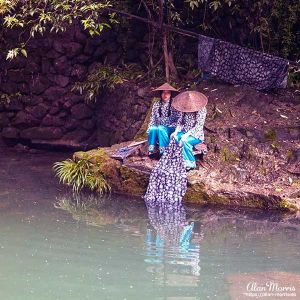 Two girls from the Tribe of the Three Gorges wash clothes in the Xiangxi River